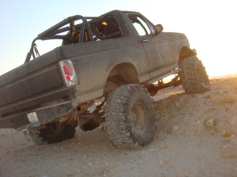 1992 Ford Bronco - This heavily modified 1992 Ford Bronco is captured in a three-quarter front view as it navigates a steep, sandy incline.