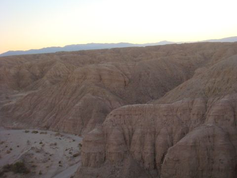 1992 Ford Bronco - A vast desert landscape unfolds under a fading sky, with layered hills showing signs of erosion.