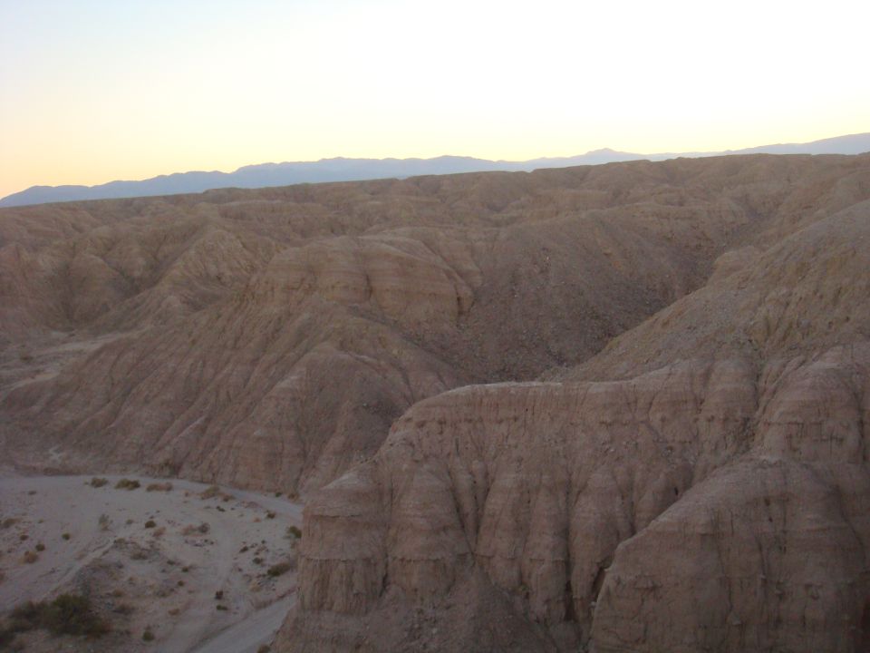 Desert landscape with eroded hills and a clear sky at sunset