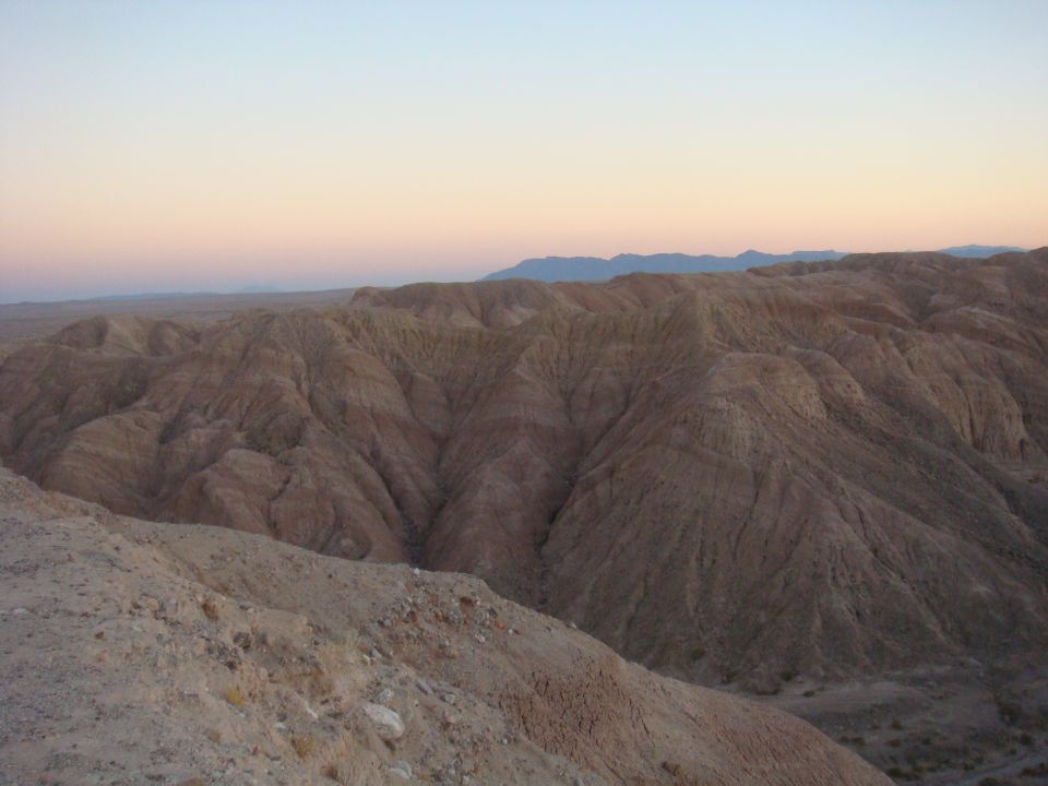 Badlands landscape with layered hills and a soft gradient sky at sunset