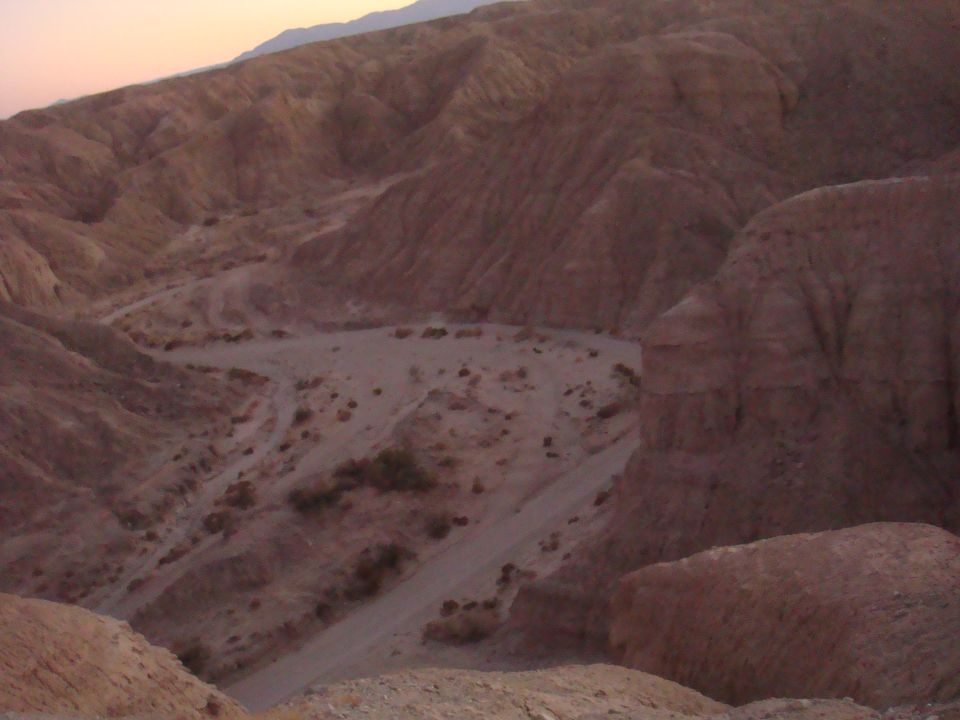 Desert landscape with a dirt road winding through hills. Supermotors.net logo visible