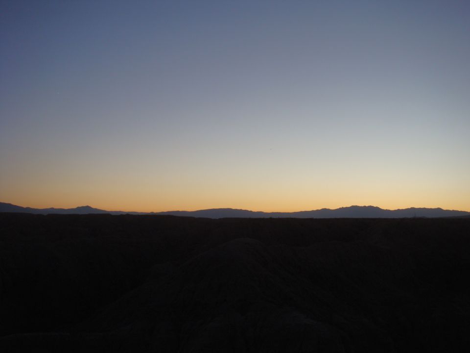 Desert hills and mountains under a gradient sky at dusk. Supermotors.net logo in lower right