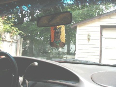 1997 Ford Taurus - View from inside a vehicle shows a Scooby-Doo air freshener hanging from the rearview mirror, with a garage visible through the windshield.