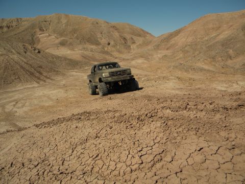 1992 Ford Bronco - A 1992 Ford Bronco navigates a , arid terrain under a clear blue sky.
