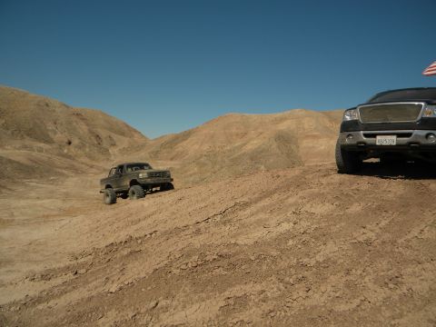 1992 Ford Bronco - Two trucks navigate a dusty, arid landscape under a clear blue sky.