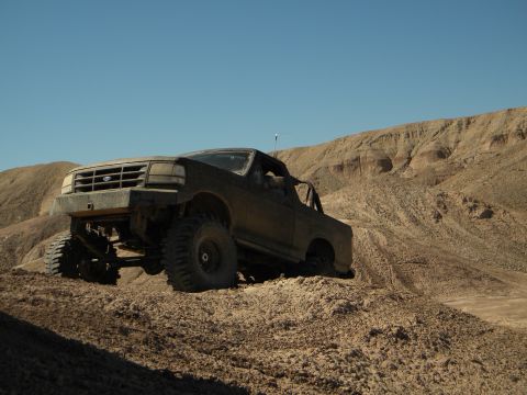 1992 Ford Bronco - This lifted 1992 Ford Bronco navigates a steep, sandy incline under a clear blue sky.