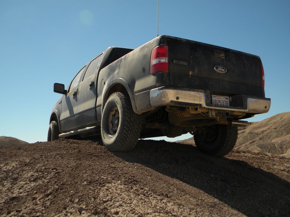 Ford F-150 pickup truck driving on dirt hill, rear view. License plate 8B25378