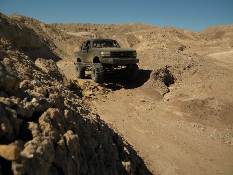 1992 Ford Bronco - A 1992 Ford Bronco navigates a rocky desert trail under a clear blue sky.