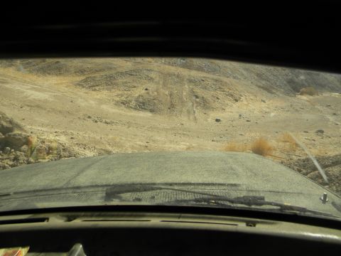 1992 Ford Bronco - Driving through a dry, rocky terrain with tire tracks visible on the hills ahead.