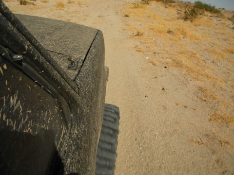 1992 Ford Bronco - Vehicle driving on a dirt road, covered in mud from off-road conditions.