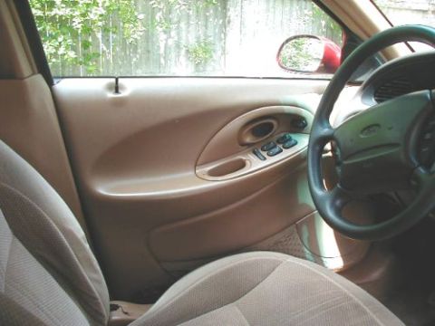 1997 Ford Taurus - The interior of a 1997 Ford Taurus is visible, including the door panel with window controls and the steering wheel.