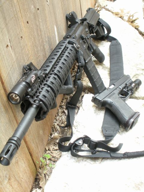 1996 Ford Bronco - Assault rifle and handgun with tactical lights are placed on a wooden surface and rocks.