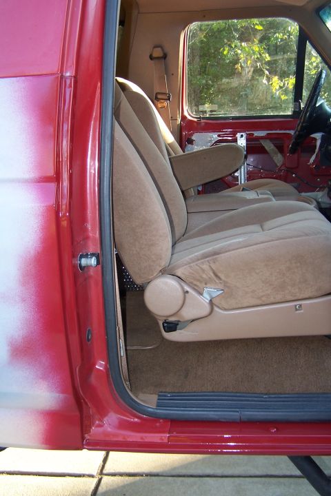 1990 Ford Bronco - The interior of a red truck shows tan bucket seats and exposed door panels.