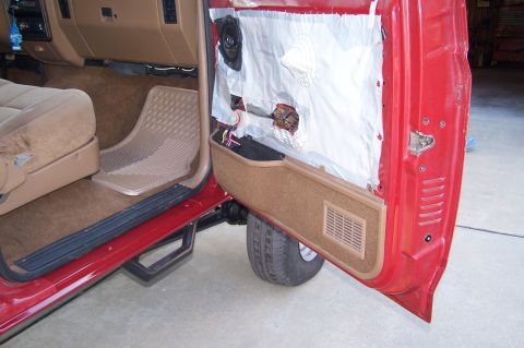 1990 Ford Bronco - Interior view of a red 1990 Ford Bronco, with the driver's side door open, revealing the dashboard and a partially removed door panel.