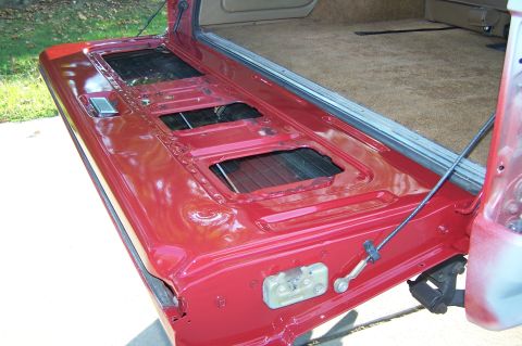 1990 Ford Bronco - The interior of a red tailgate reveals its latch mechanism and open cargo space, consistent with a 1990 Ford Bronco.