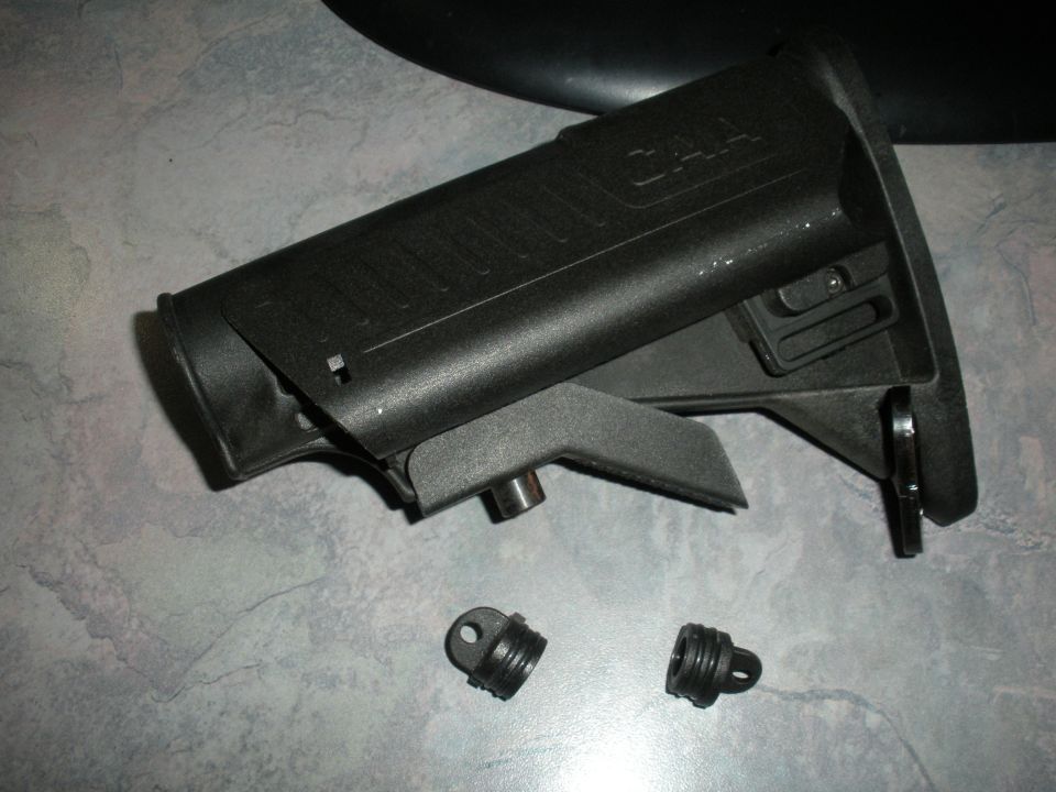 black gun stock with "CAA" logo, two small threaded parts nearby