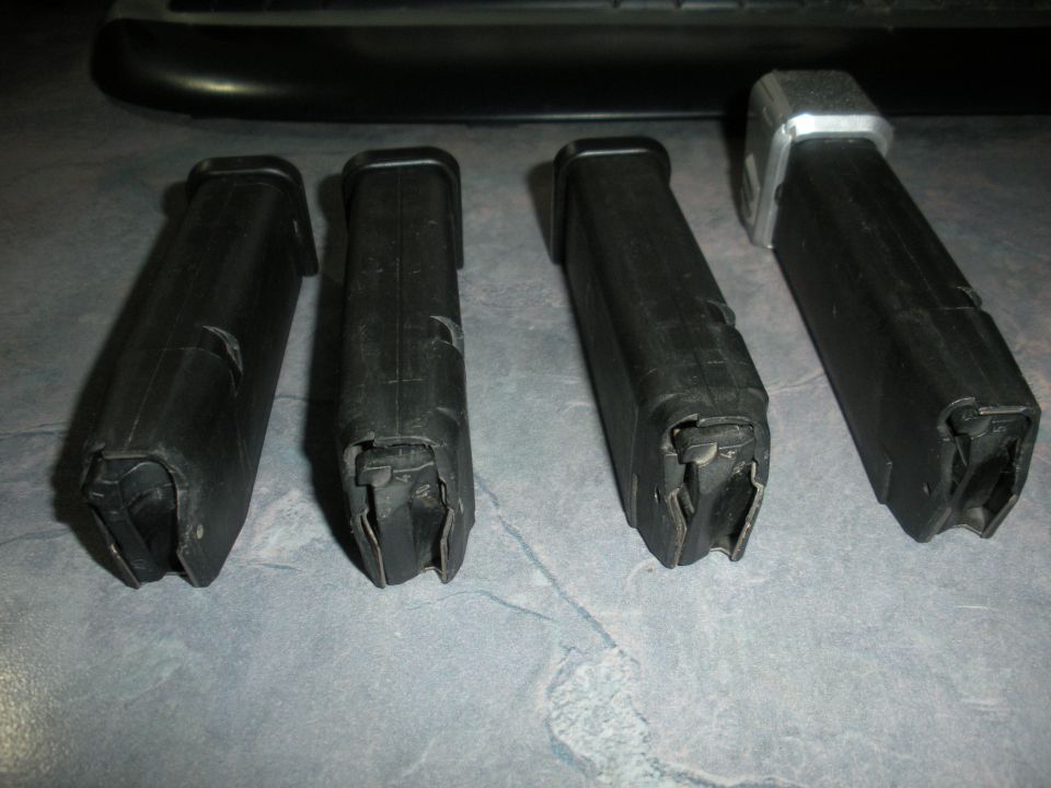 Four black pistol magazines on a gray surface
