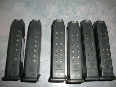 1996 Ford Bronco - A collection of six black gun magazines, some with visible caliber markings, are laid out on a textured surface.