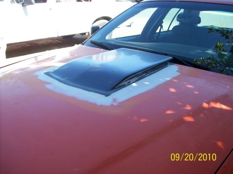 2002 Ford Crown Victoria - Installing a hood scoop on an orange car, with primer visible around the edges.