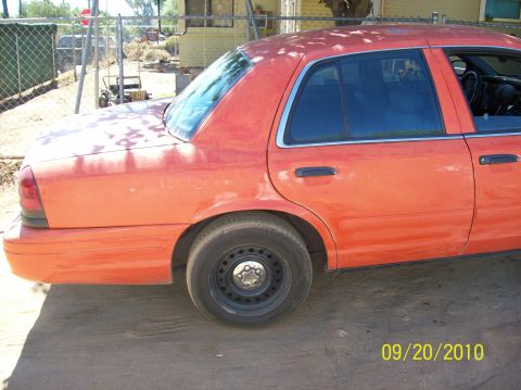 2002 Ford Crown Victoria - Side view of an orange 2002 Ford Crown Victoria parked outdoors.