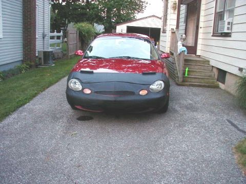 1997 Ford Taurus - A red 1997 Ford Taurus is parked on a gravel driveway, partially covered by a black car bra.