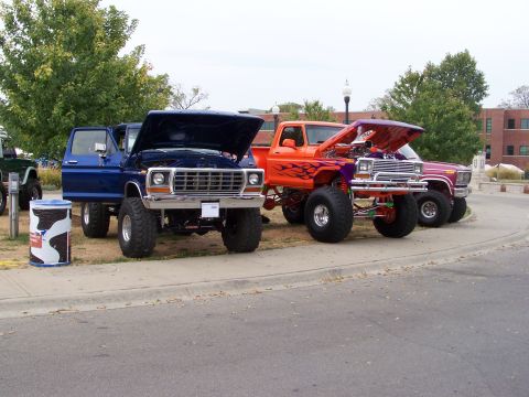 1989 Ford Bronco - Multiple lifted Ford trucks displayed with their hoods open at an outdoor event.