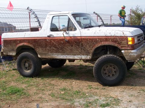 1989 Ford Bronco - This muddy 1989 Ford Bronco is seen from the side, its two-tone paint job and off-road tires.