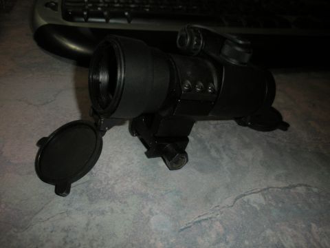 1996 Ford Bronco - A black optical scope with its lens cap open sits on a textured surface.