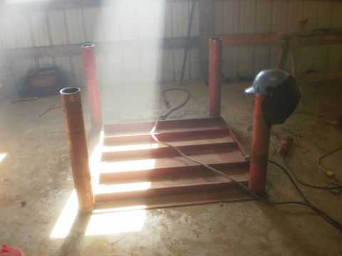 1995 Ford Bronco - A metal structure with red posts and a stepped platform is shown in a workshop setting, with a welding helmet nearby.