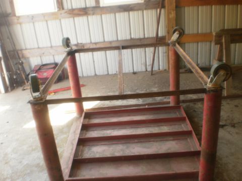 1995 Ford Bronco - A red metal platform with wheels and a metal frame is shown in a workshop setting.