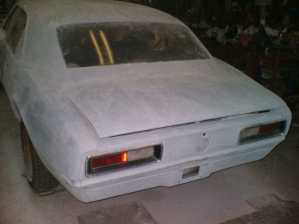 Unpainted car rear with rectangular taillights and chrome trim