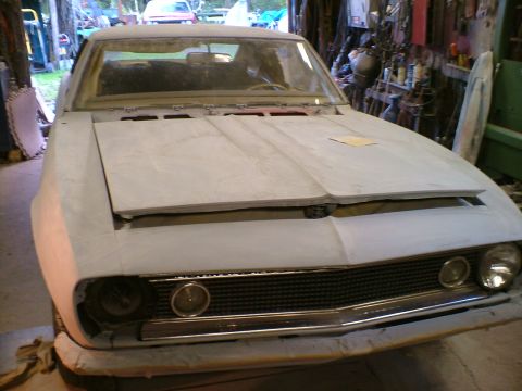 1989 Ford Bronco - This car, possibly a Chevrolet Camaro, is in a state of repair or restoration, with its hood open and bodywork unfinished.