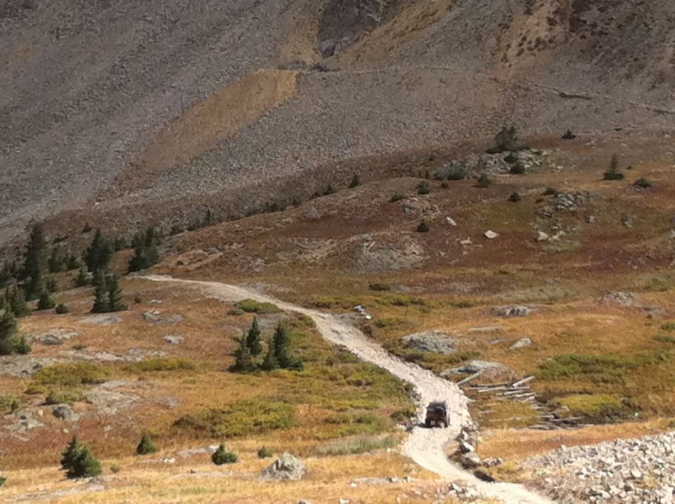 SUV driving up a dirt road on a rocky mountainside