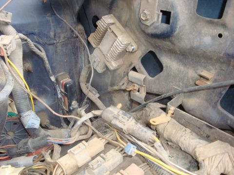 1989 Ford Bronco - Close-up inside a dusty engine bay showing the inner fender and radiator support with a finned TFI ignition module mounted to the sheet met…