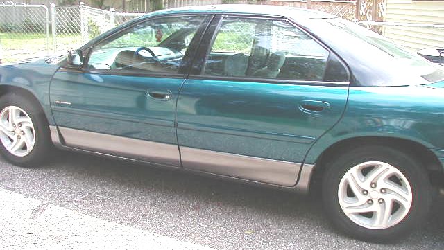 Teal green four-door sedan side profile with gray lower cladding and alloy wheels