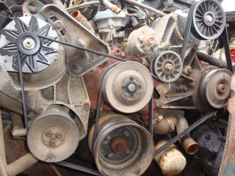 Front of a dusty V8 engine showing alternator, pulleys and serpentine belt