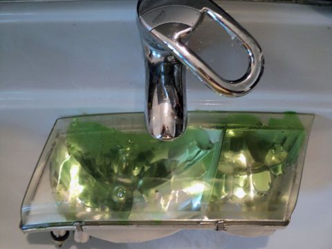 2001 Mercury Grand Marquis - Headlight assembly soaking in a sink with a chrome faucet overhead.