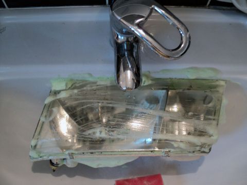 2001 Mercury Grand Marquis - A headlight assembly is being cleaned with soap and water in a sink.