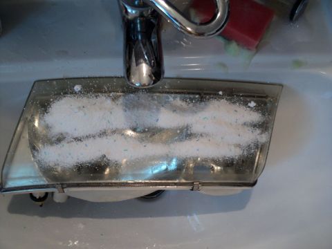 2001 Mercury Grand Marquis - A headlight assembly is being cleaned with powder under a faucet in a sink.