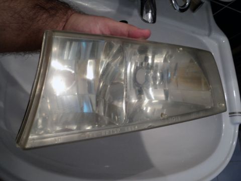 2001 Mercury Grand Marquis - A headlight assembly is held over a sink, showing signs of yellowing and wear.