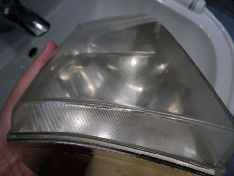 2001 Mercury Grand Marquis - Car headlight assembly being held over a sink, likely for cleaning or restoration.