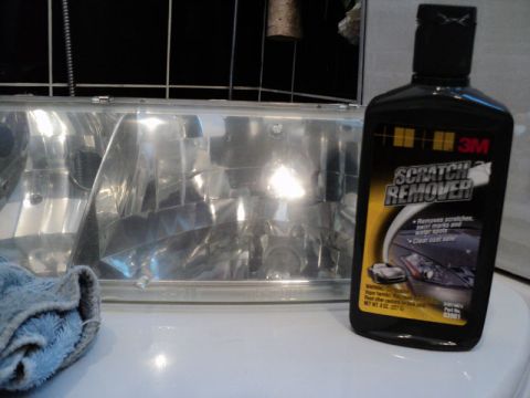 2001 Mercury Grand Marquis - A headlight assembly sits on a white surface next to a bottle of 3M scratch remover and a cleaning cloth.