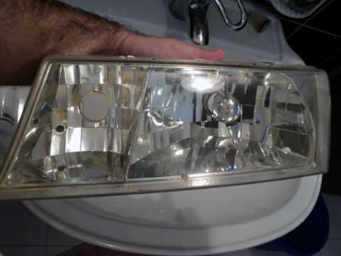 2001 Mercury Grand Marquis - A single headlight assembly is held over a sink, likely for cleaning or restoration.