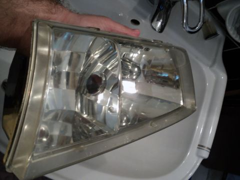 2001 Mercury Grand Marquis - A car headlight is held over a sink, likely for cleaning or restoration.