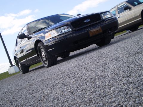 2003 Ford Crown Victoria - Front 3/4 view of a black 2003 Ford Crown Victoria on a gravel lot.