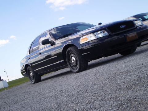 2003 Ford Crown Victoria - A black 2003 Ford Crown Victoria is shown from a low angle, highlighting its front three-quarter view.