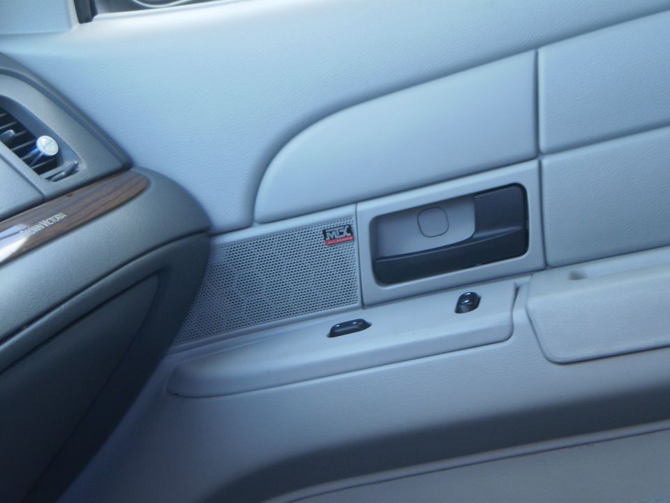 Interior door panel of a 2003 Ford Crown Victoria, showing speaker grille and door handle