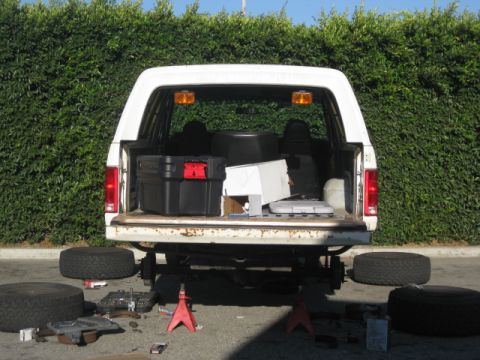 1986 Ford Bronco - 1986 Ford Bronco rear view with tailgate open, spare tires and tools scattered around.
