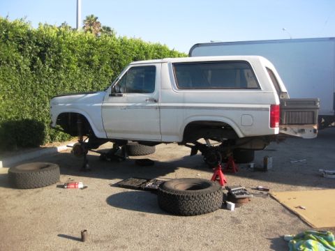 1986 Ford Bronco - This SUV is elevated on jack stands with its wheels off, indicating it is undergoing repairs or maintenance.