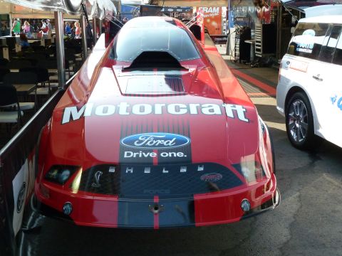 1992 Ford Mustang - A red drag car with prominent Motorcraft and Ford branding is parked next to a white SUV.